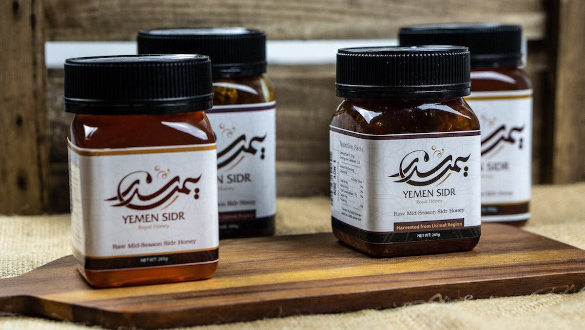 Four jars of Yemen Sidr honey on a wooden serving board against weathered timber